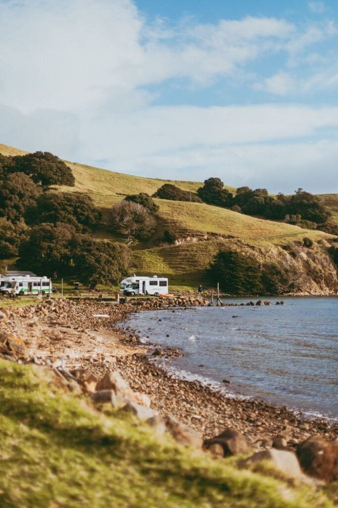 Explore the serene coastline of Coromandel with RVs parked by the sea.