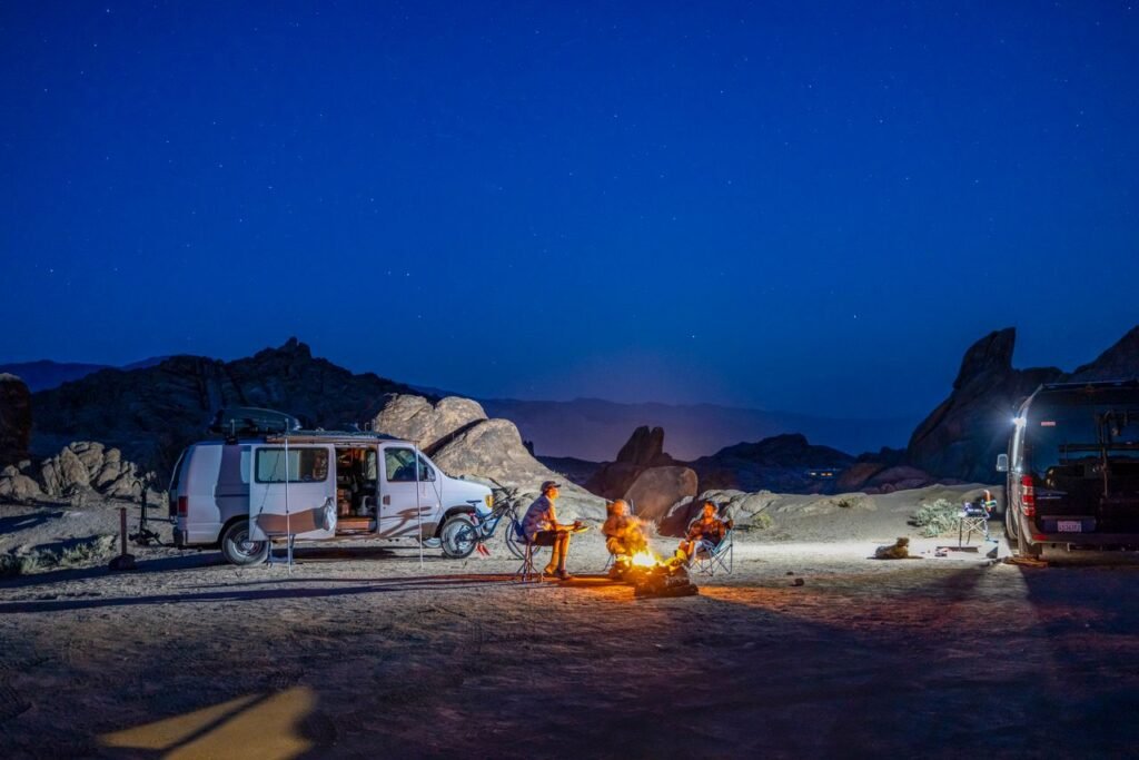 Group camping around a campfire in a rocky landscape, enjoying the starry night.