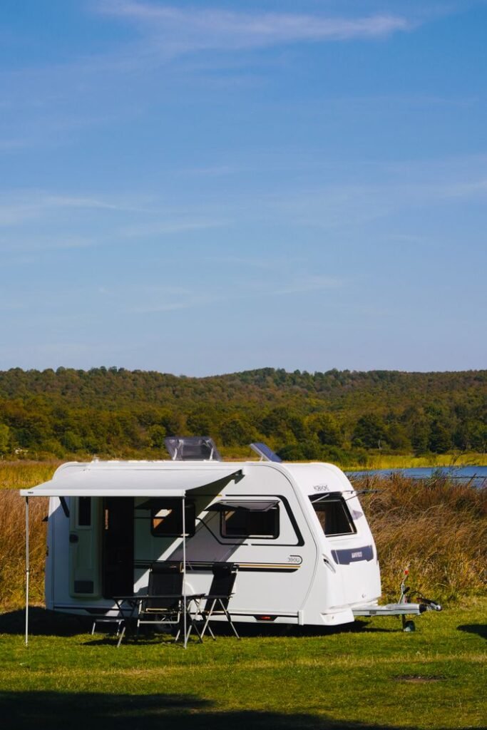 A camper van parked by a lakeside, surrounded by nature on a sunny day.