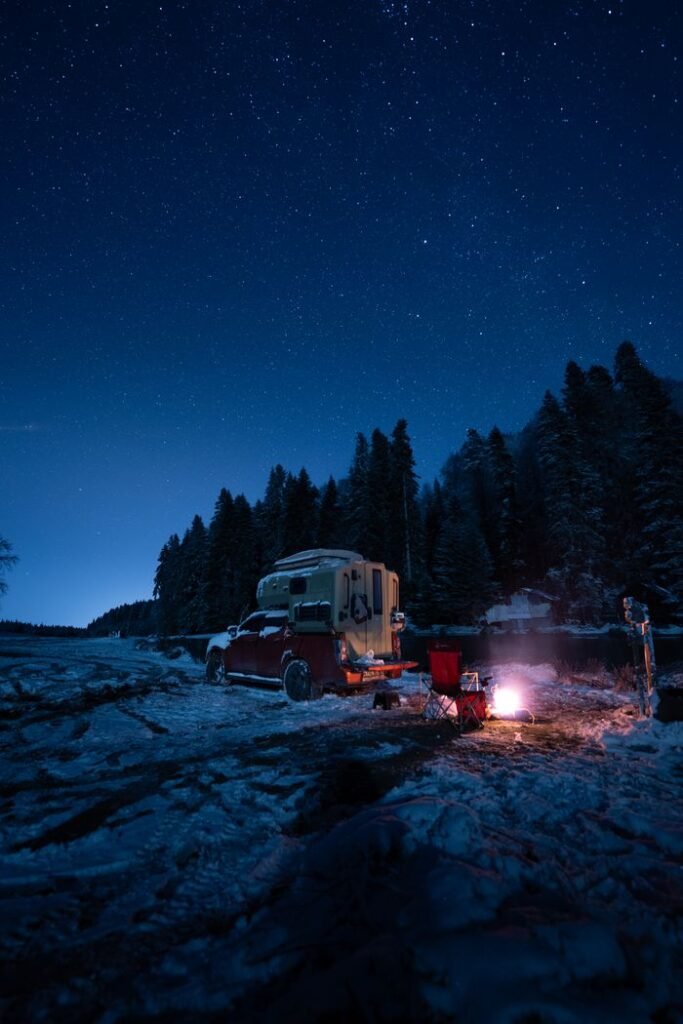 Winter camping scene with a camper, campfire, and starry sky. Perfect for travel and adventure themes.
