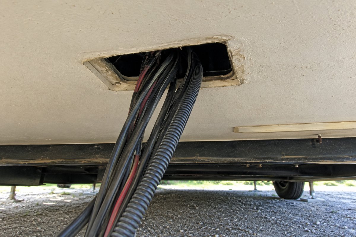 Unsealed opening around the wiring harness in the underbelly panel of a travel trailer, the gap that has to be closed to keep mice out of an RV in winter storage