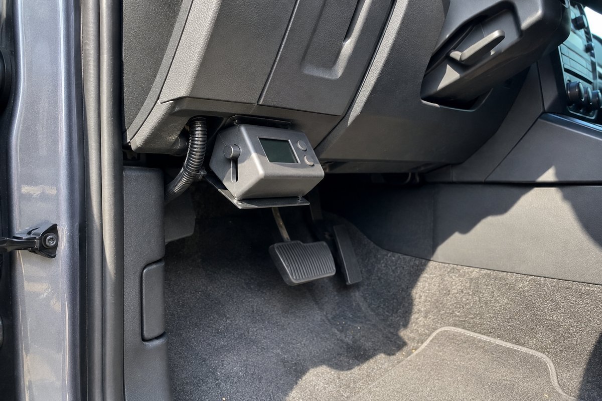 Aftermarket trailer brake controller mounted under the dash of a pickup with the display switched off