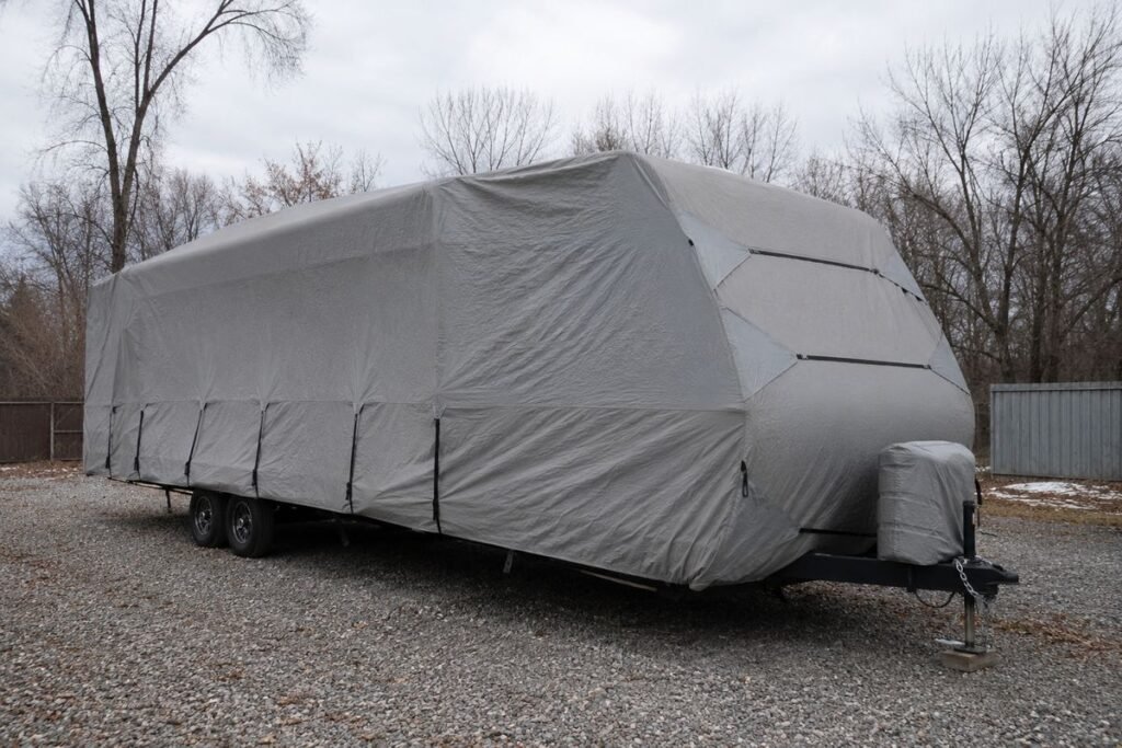 Travel trailer under an RV cover in a winter storage lot